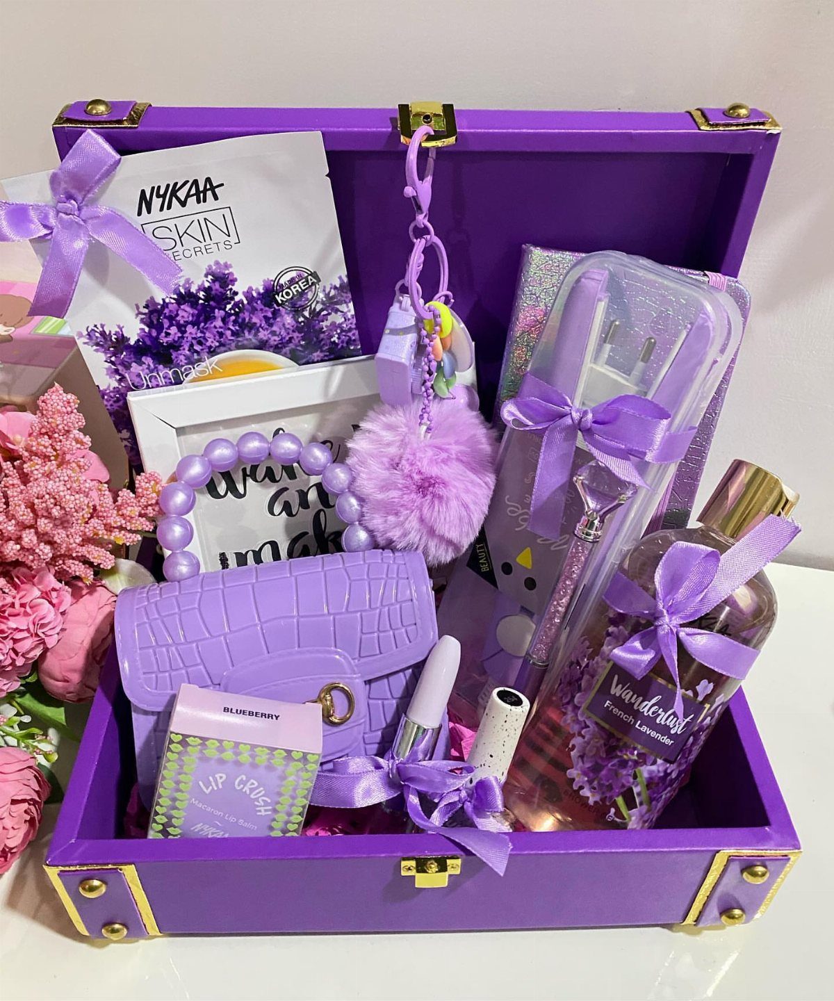 Purple gift box filled with a purse, perfume, skincare, and purple accessories.