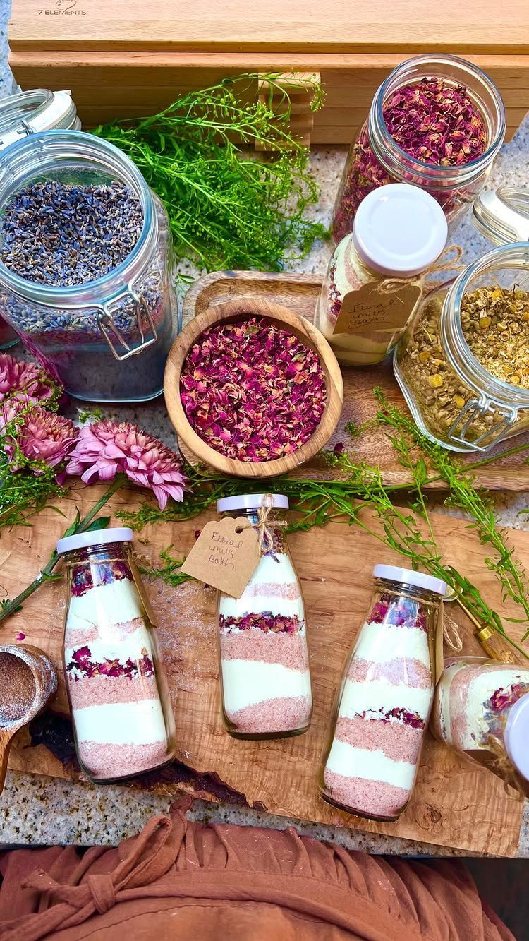 Layered herbal bath salts in small glass bottles surrounded by dried flower petals.