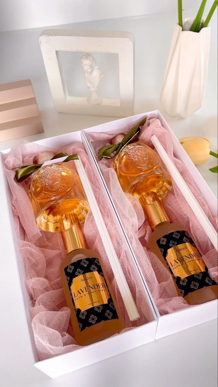 Two lavender scented spray bottles with rose caps in white gift boxes