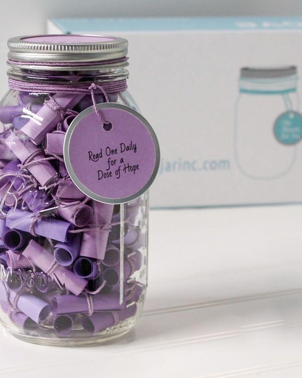 Glass mason jar filled with purple paper scrolls and a hope tag.