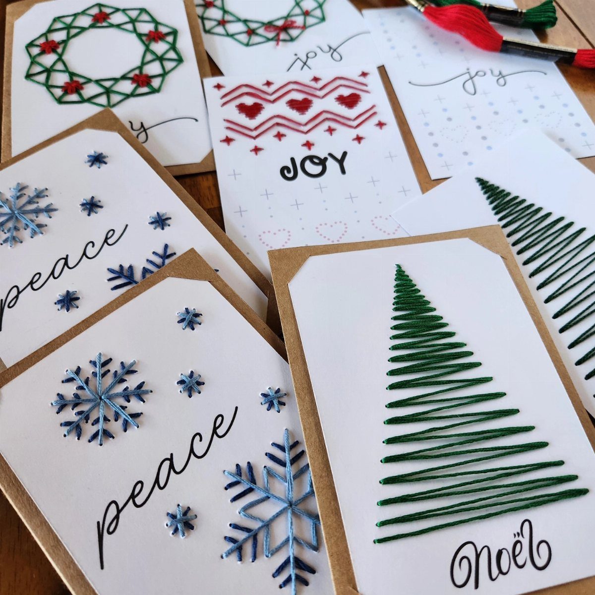 Handmade holiday cards with embroidered green trees, blue snowflakes, and red wreaths.