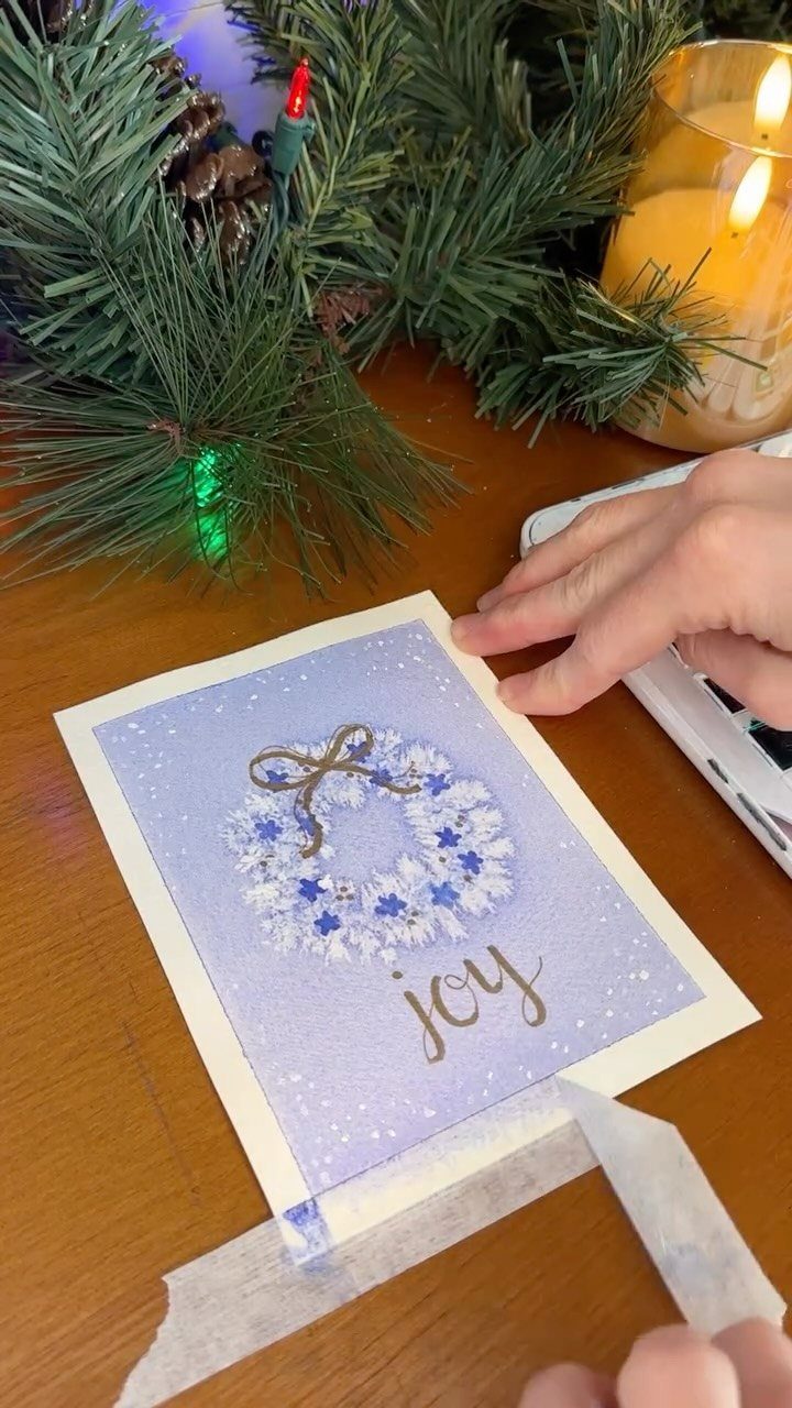 Purple Christmas card with a glittery wreath and gold joy lettering on wooden table