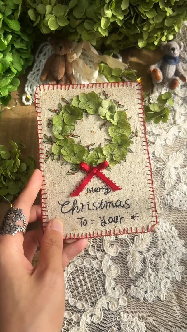 Handmade Christmas card featuring a wreath of green leaves and a red bow.