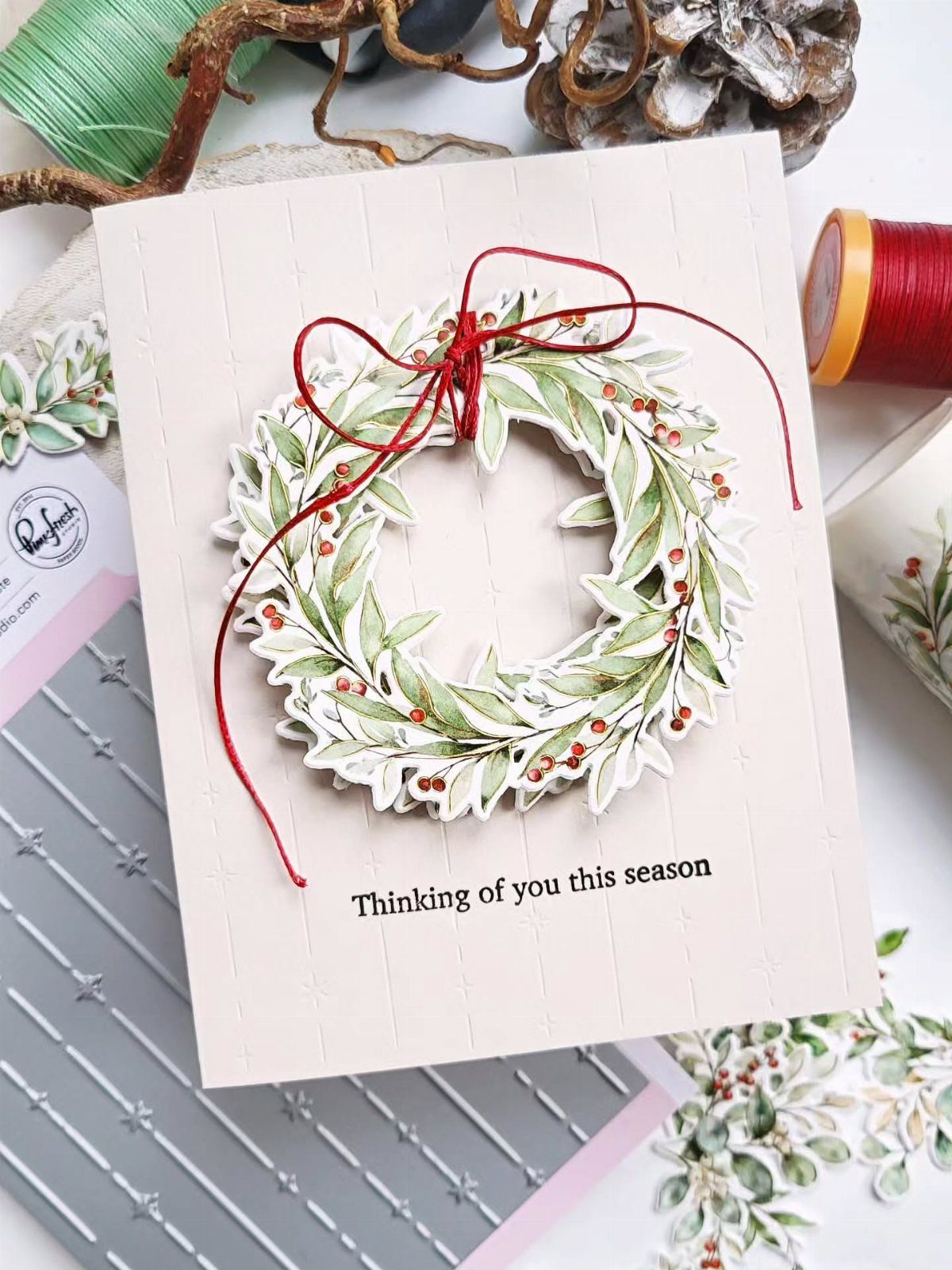 White greeting card with a layered paper wreath and red string bow.