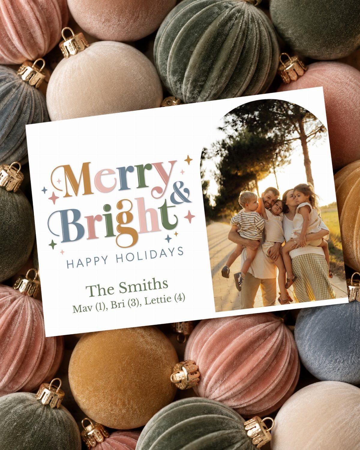 Holiday card with family photo resting on colorful velvet Christmas ornaments.