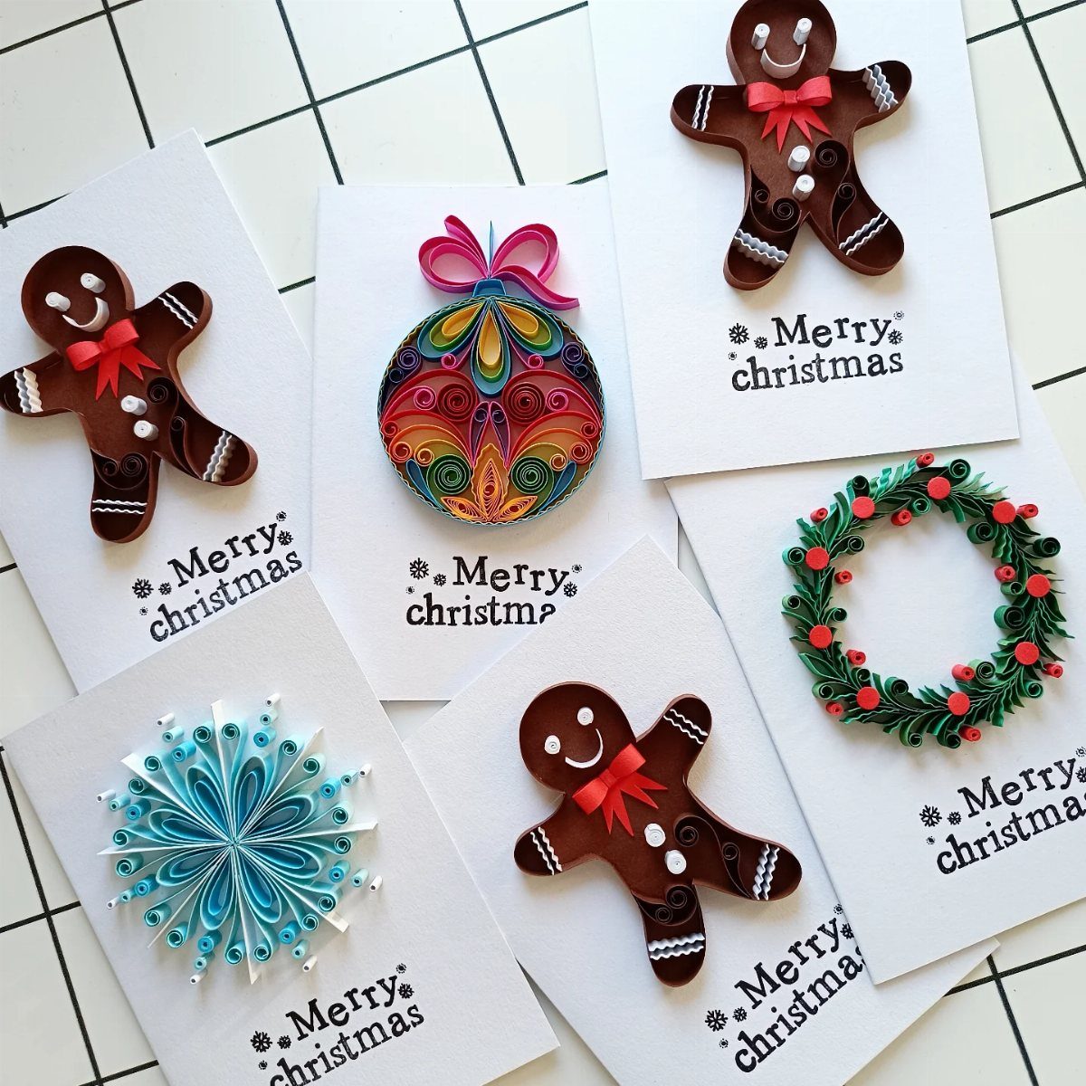 Six white Christmas cards featuring 3D quilled paper gingerbread men, ornaments, and snowflakes.