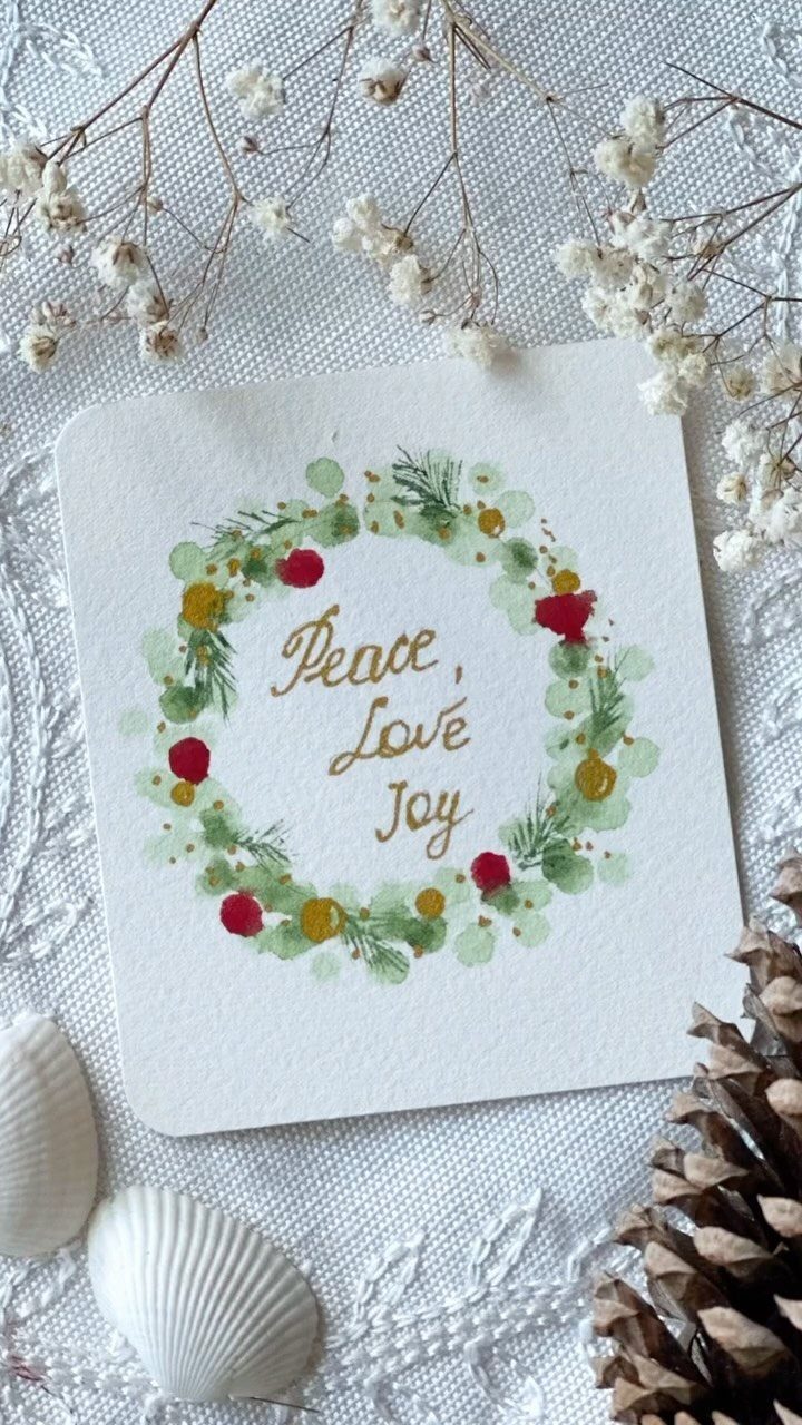 Watercolor card with a painted wreath and text surrounded by natural winter elements