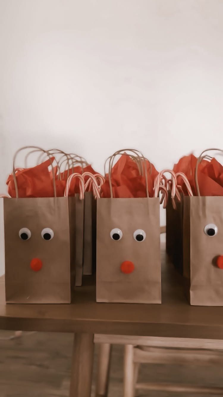 Brown paper gift bags decorated as reindeer with googly eyes and red noses.