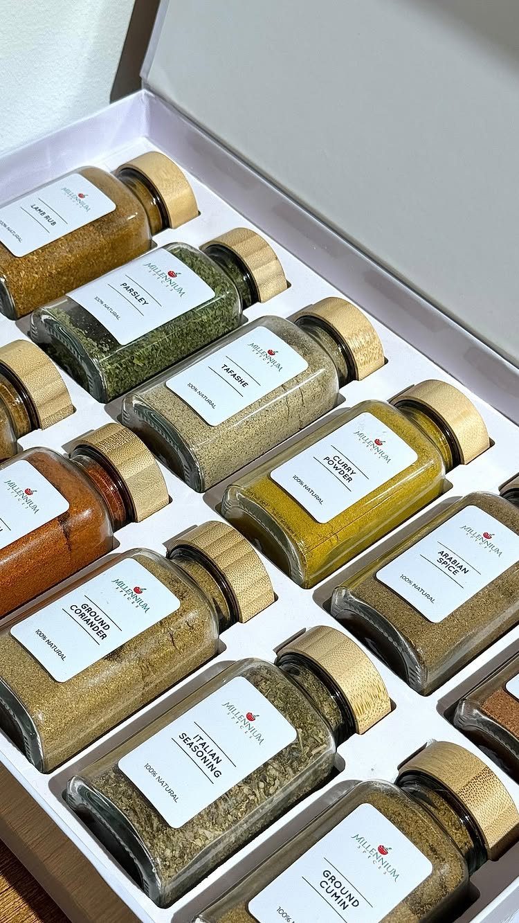Glass jars of various ground spices arranged in a white gift box.