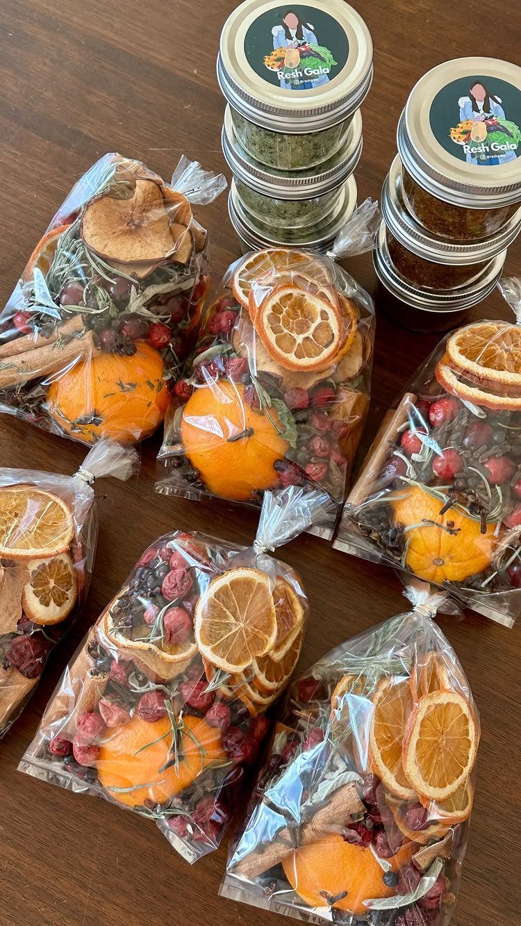Dried orange slices, cinnamon, and berries in clear gift bags on wooden table