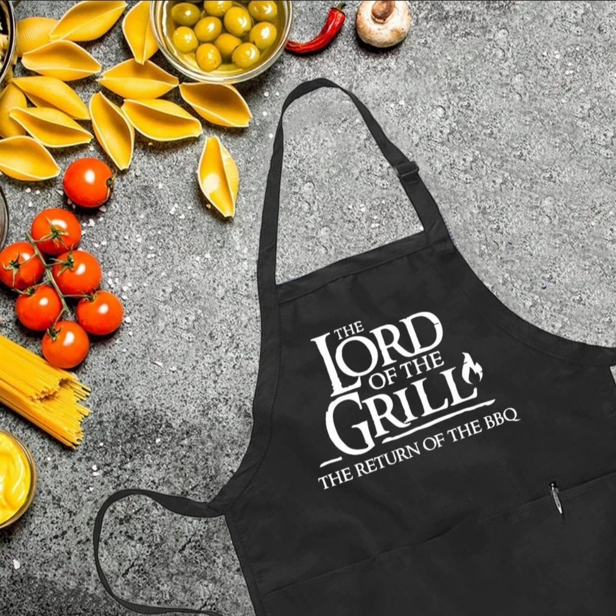 Black apron with Lord of the Grill text surrounded by fresh cooking ingredients.