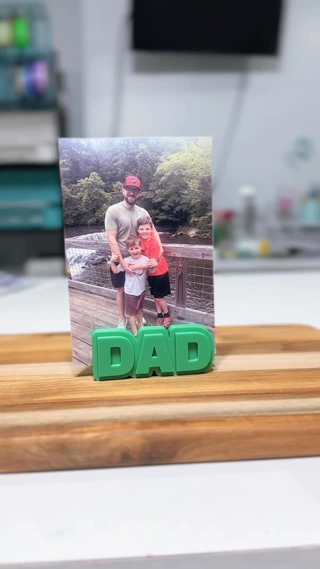 Family photo held up by green DAD letters on a wooden board