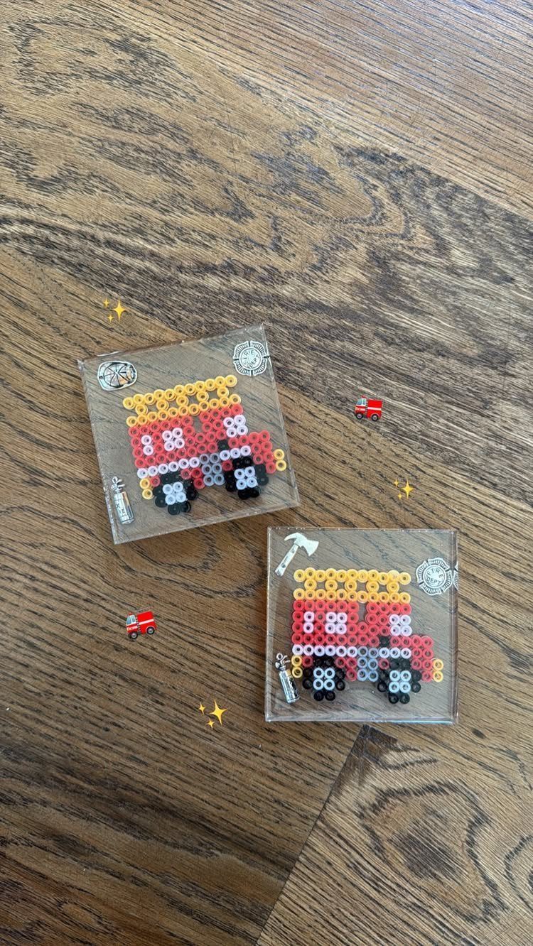 Two clear acrylic coasters with red fire truck bead art on wooden table