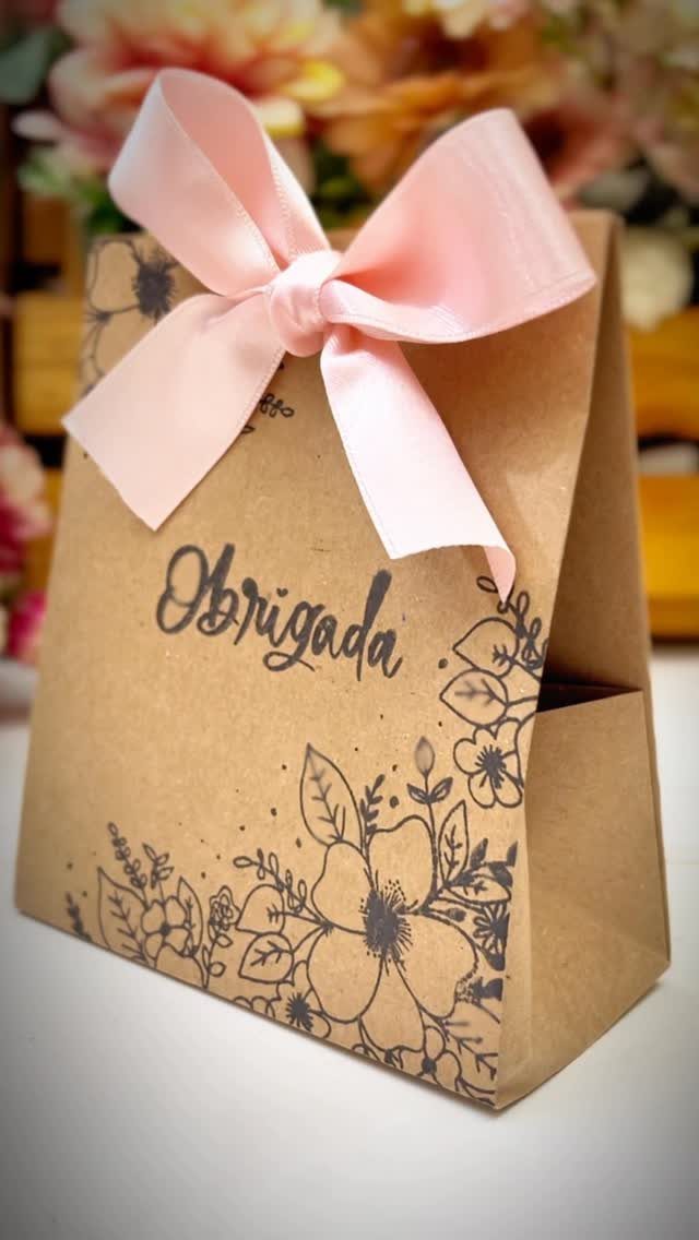 Brown kraft paper gift bag with floral drawings and a pink satin bow.