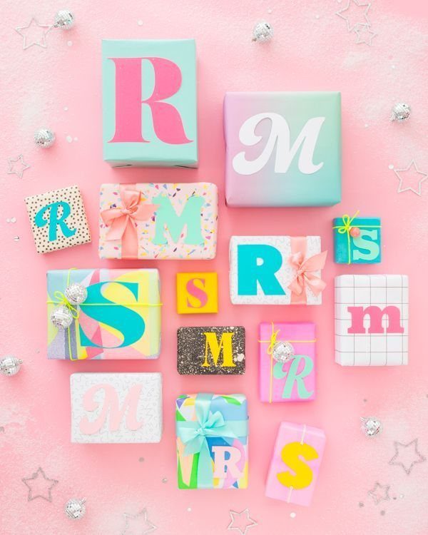 Colorful wrapped gift boxes with large typographic letters on a pink background