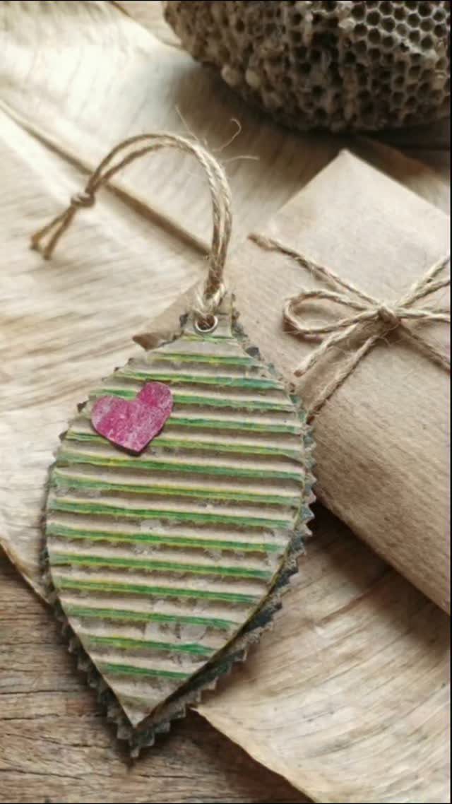 Leaf-shaped corrugated cardboard gift tag with a pink heart on brown paper package