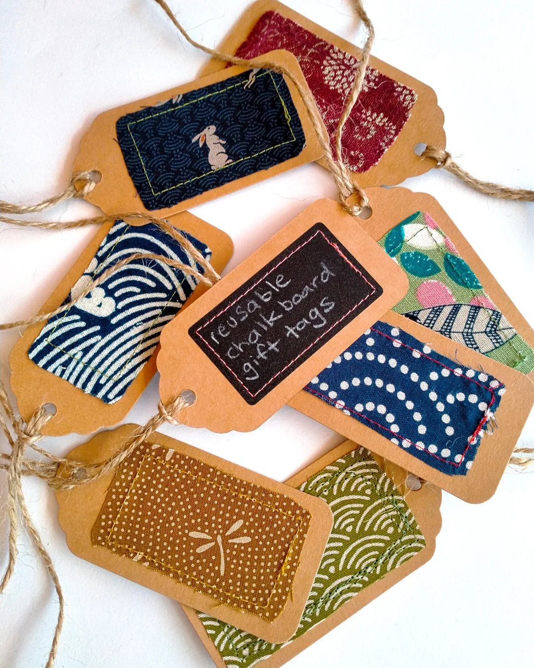 Brown cardboard gift tags decorated with colorful patterned fabric scraps and twine strings.