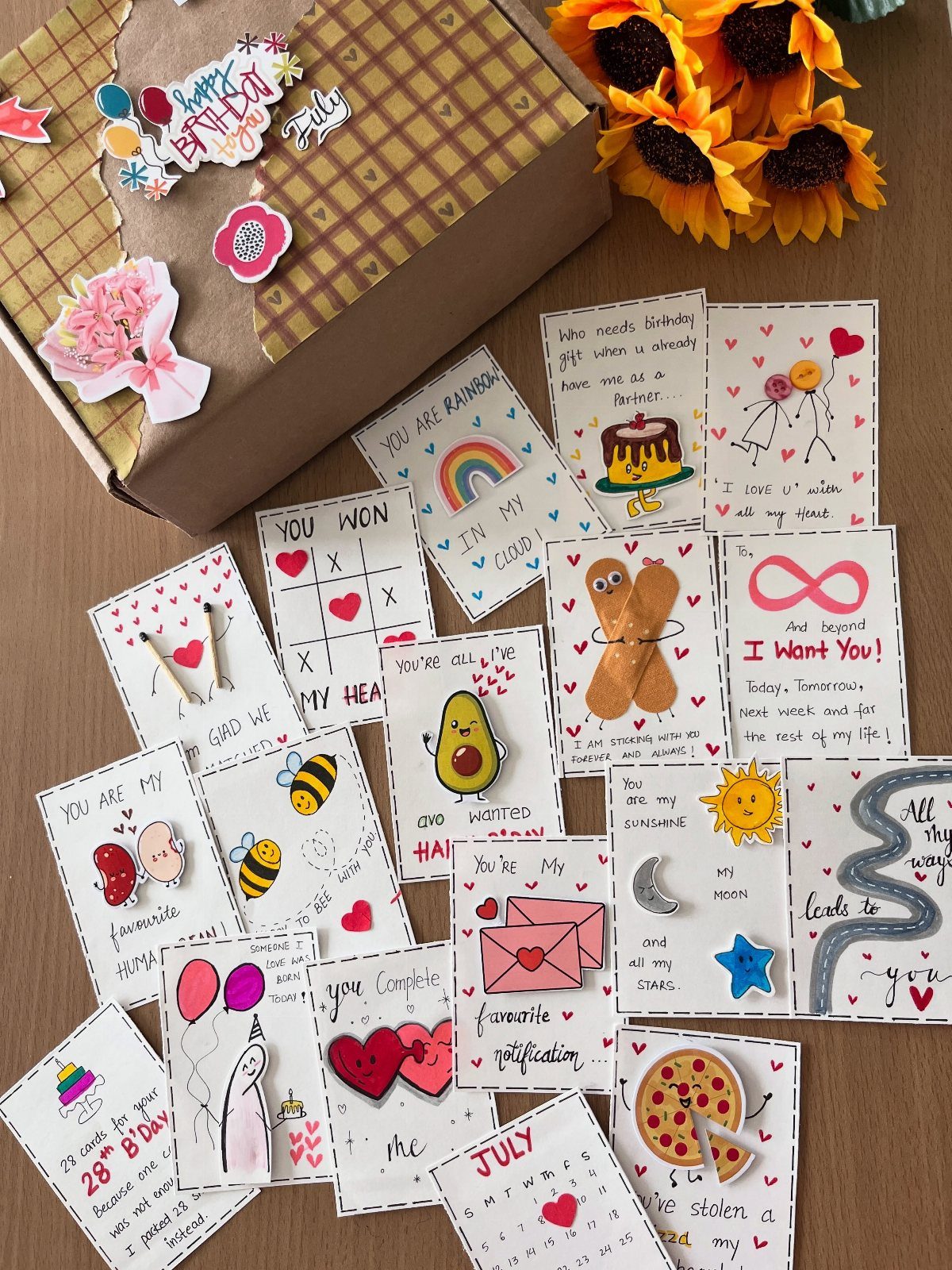 Handmade white gift tags with colorful illustrations and messages on a wooden table.