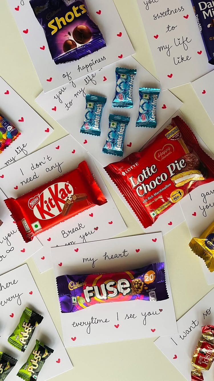 Assorted chocolates and candies on white cards with handwritten romantic love notes.