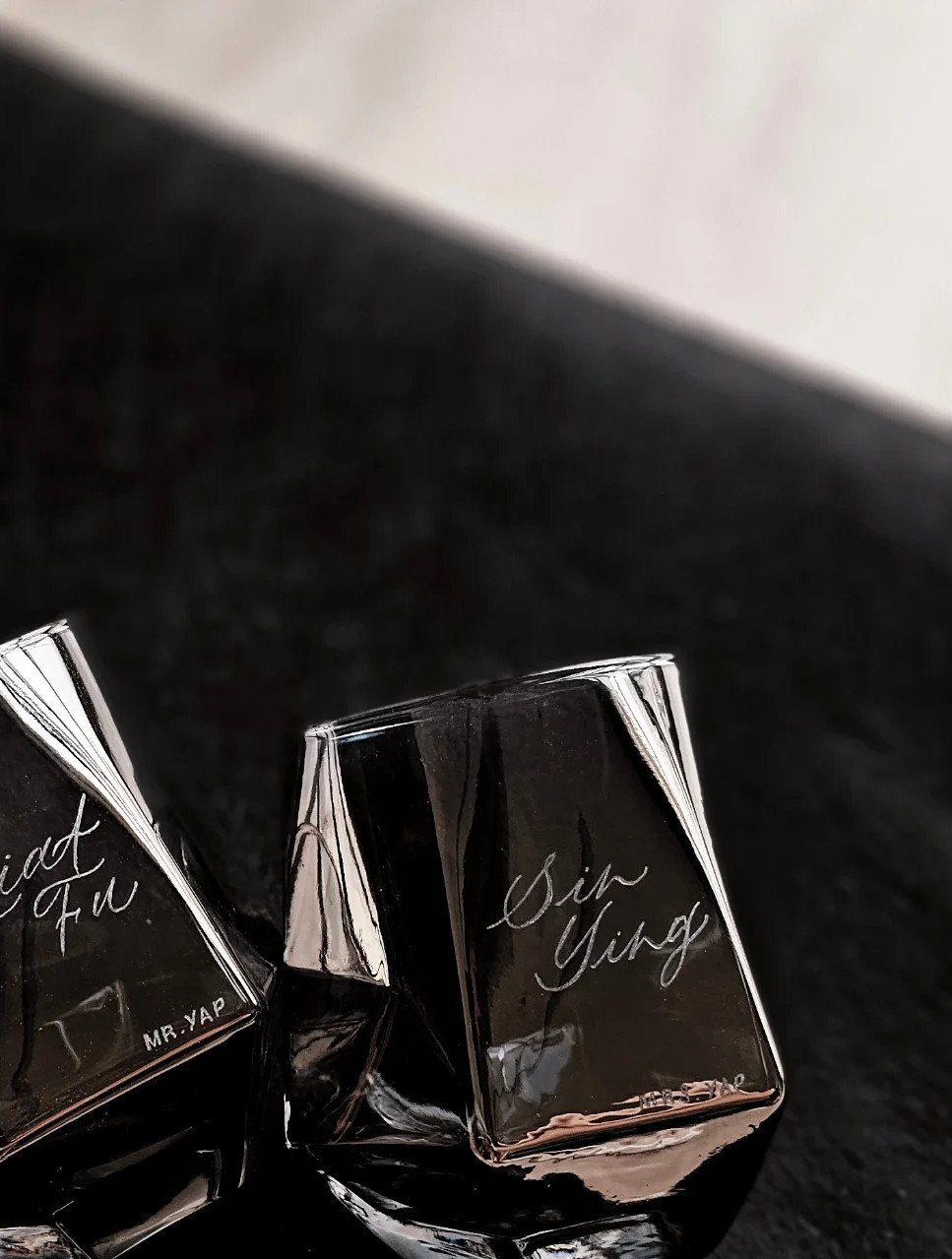 Two black square glasses with personalized names etched in white cursive script.