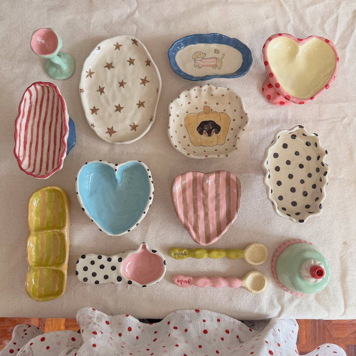 Handmade colorful clay jewelry bowls and spoons with various patterns on beige fabric