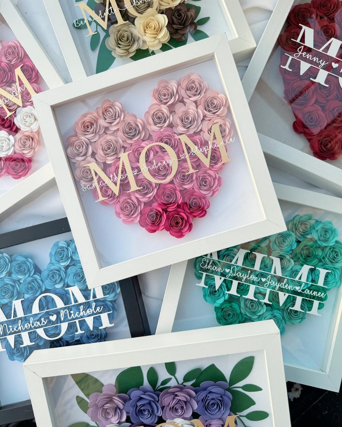 Heart-shaped paper rose arrangements in white frames with the word MOM in gold.