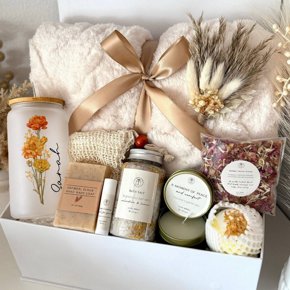 Gift box with a fluffy white blanket, personalized candle, and handmade spa products.