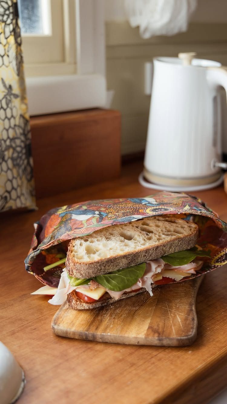 Sandwich on sourdough bread partially wrapped in a colorful patterned beeswax food wrap.