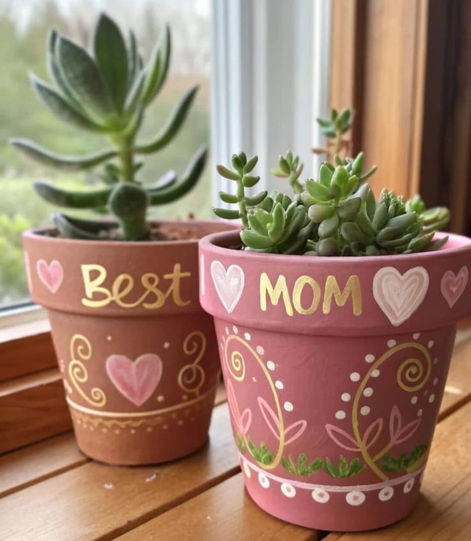 Two painted terracotta pots with succulents, decorated with hearts and the words Best Mom.