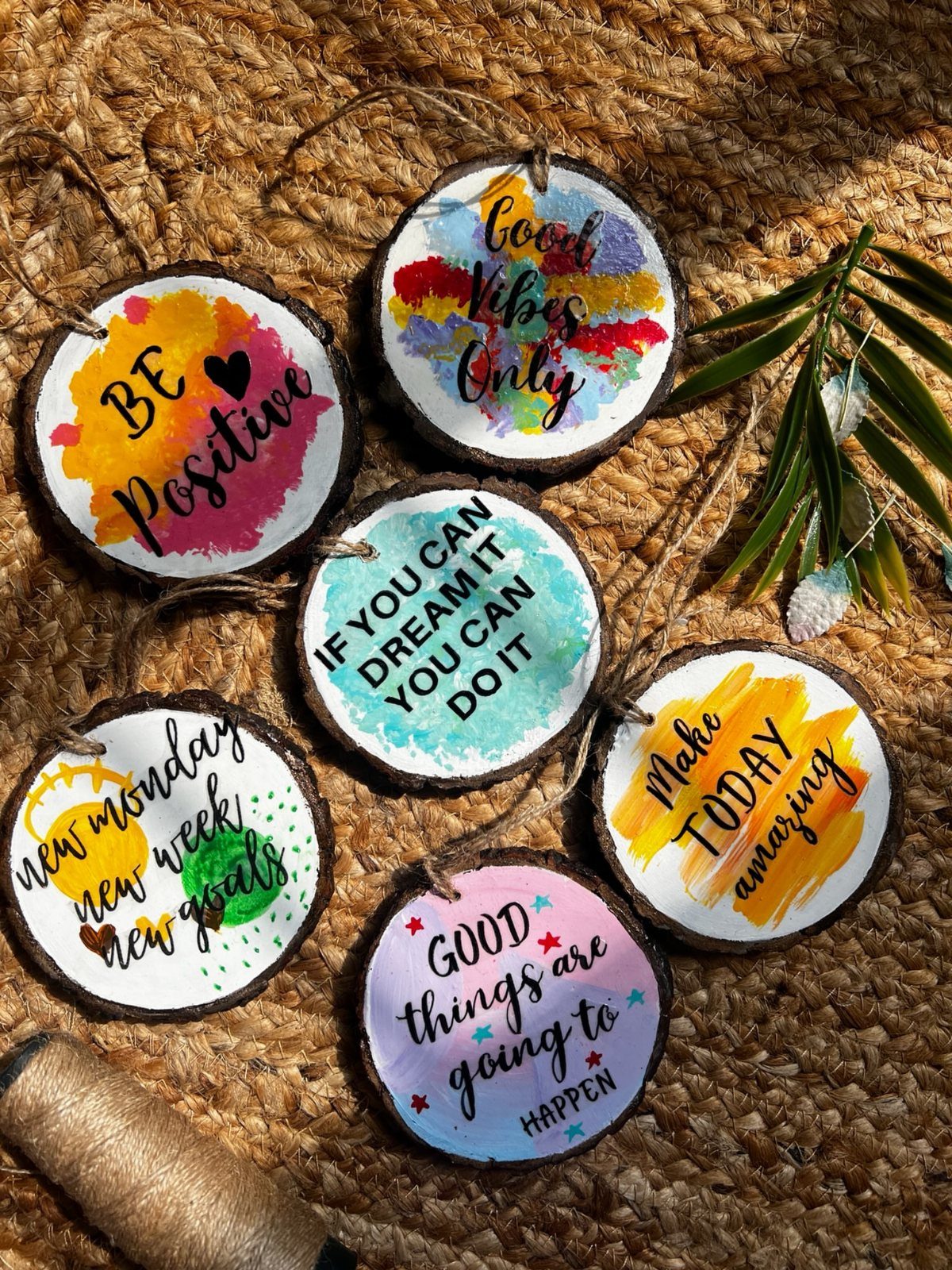 Circular wooden slices with colorful painted backgrounds and motivational quotes on woven mat
