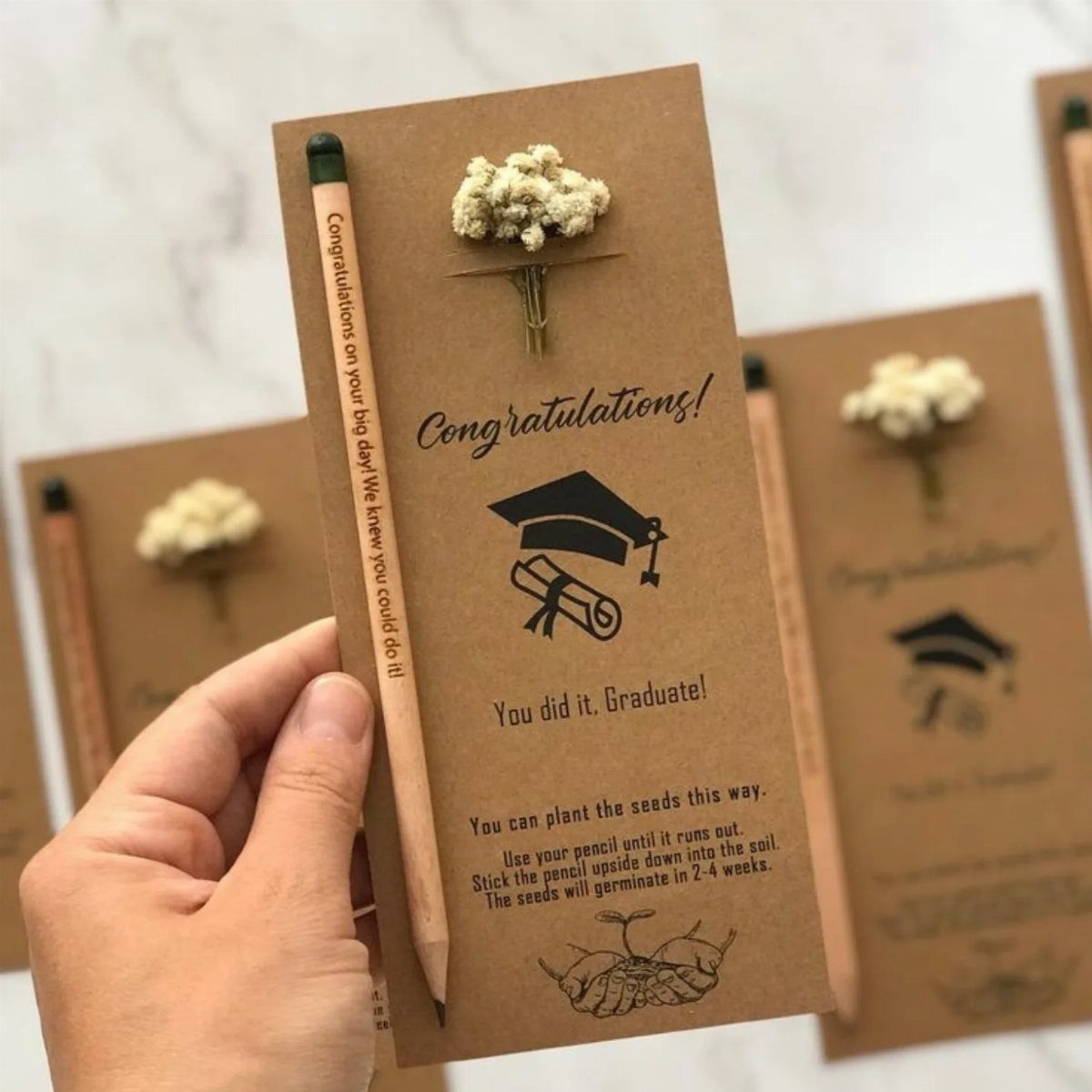 Graduation card with a pencil and dried flower on brown cardboard background