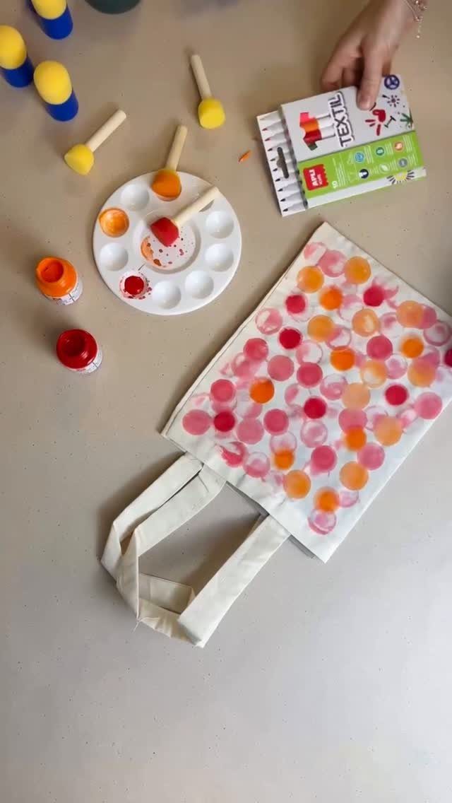 White canvas tote bag with colorful painted dots and art supplies on table