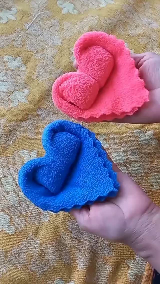 Heart-shaped plush fleece items in pink and blue held by two hands.