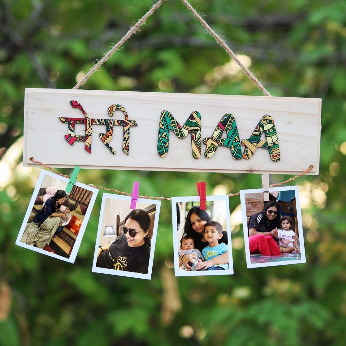 Wooden plaque with colorful lettering and hanging family photos against green leaves