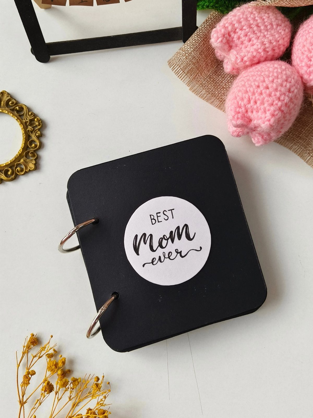 Small black handmade book with 'BEST Mom ever' sticker and silver ring binding.