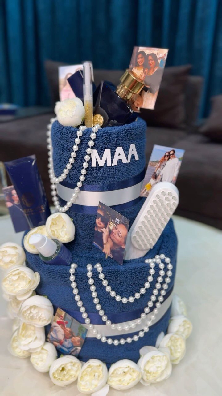 Blue towel cake gift decorated with pearls, photos, and white fabric roses.