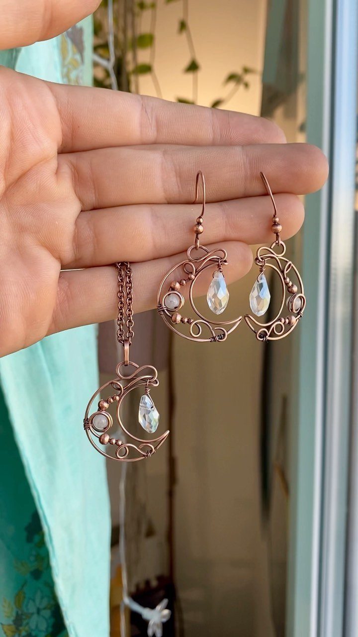 Copper wire crescent moon necklace and earrings with clear crystals held in a hand.