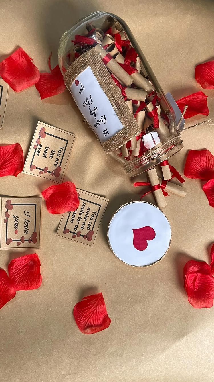 Glass jar filled with rolled love notes surrounded by red rose petals