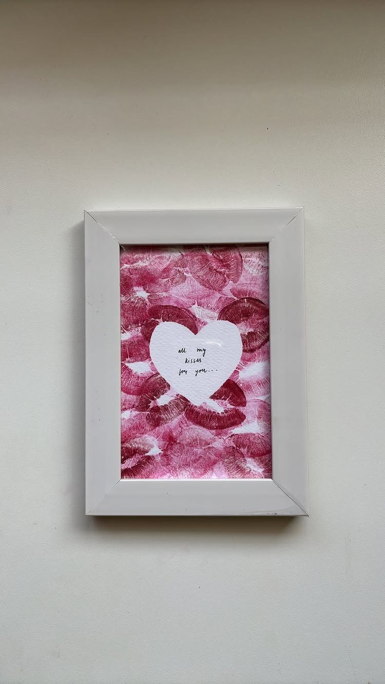 Framed lipstick kiss prints with a white heart cutout and handwritten message.