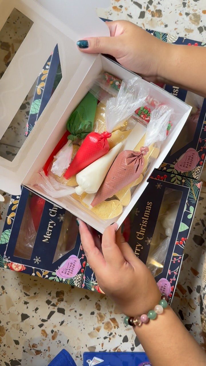 Cookie decorating kit with piping bags and plain cookies in a white box.