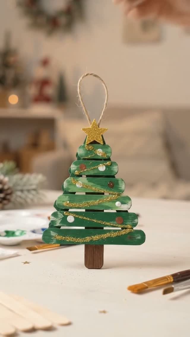 Green craft stick Christmas tree ornament with gold glitter star and twine loop.