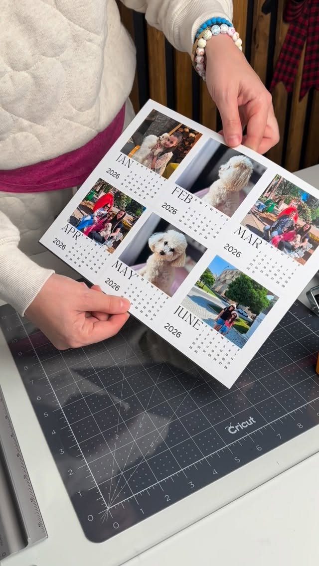 Hands holding a custom printed calendar with family and pet photos over a cutting mat