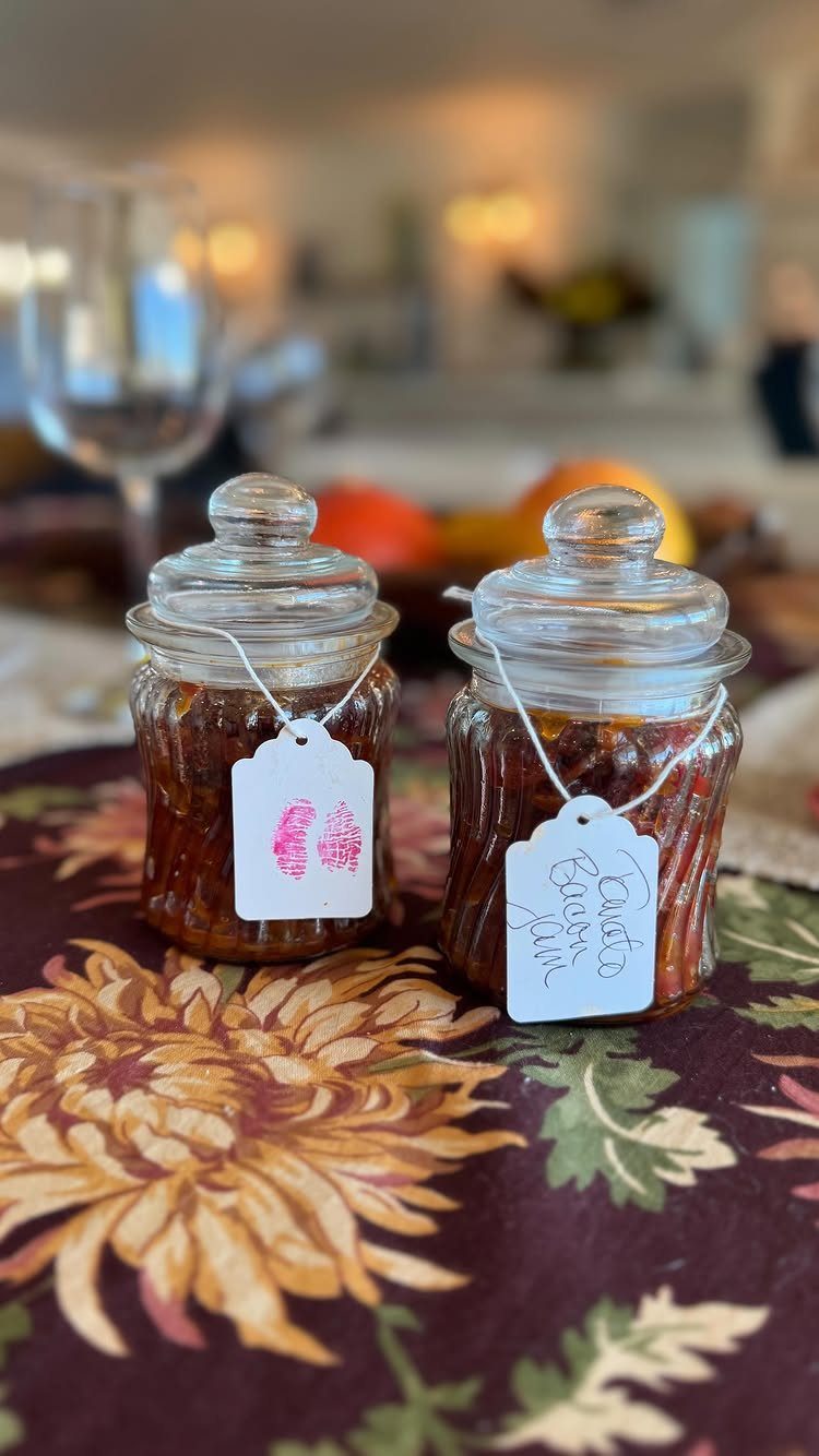 Two glass jars of homemade jam with white gift tags on floral tablecloth