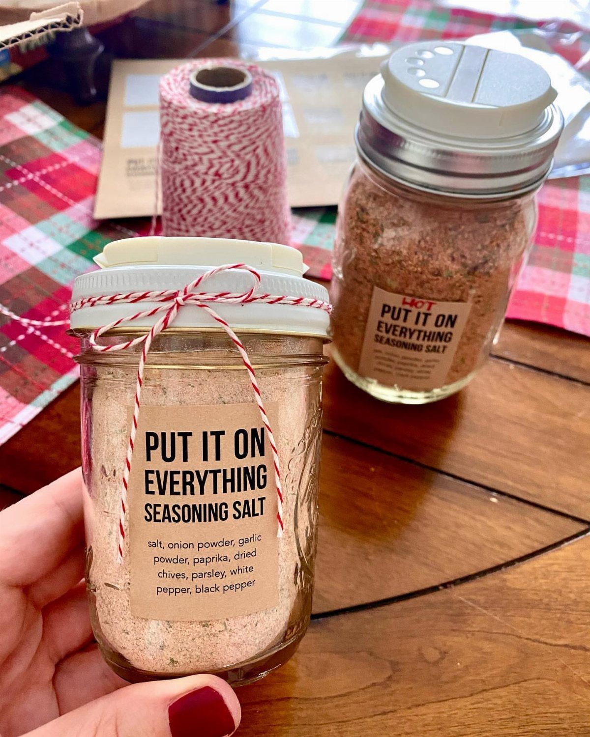 Two glass jars of homemade seasoning salt with a red and white twine bow.