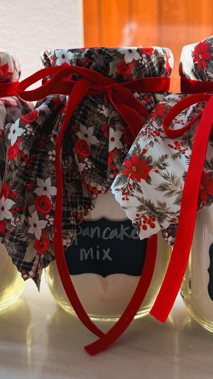 Glass jars of pancake mix with floral fabric lids and red ribbons.