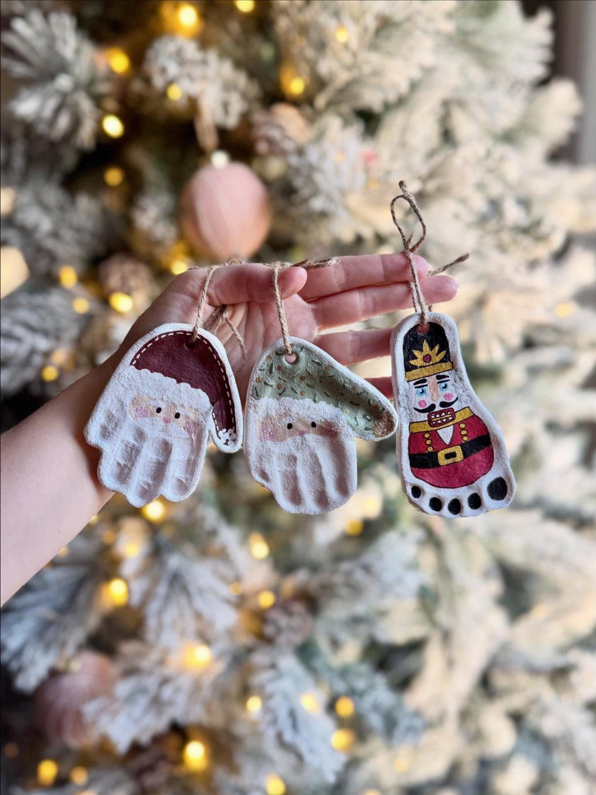 Handmade salt dough footprint ornaments painted as Santa and nutcracker before a Christmas tree.