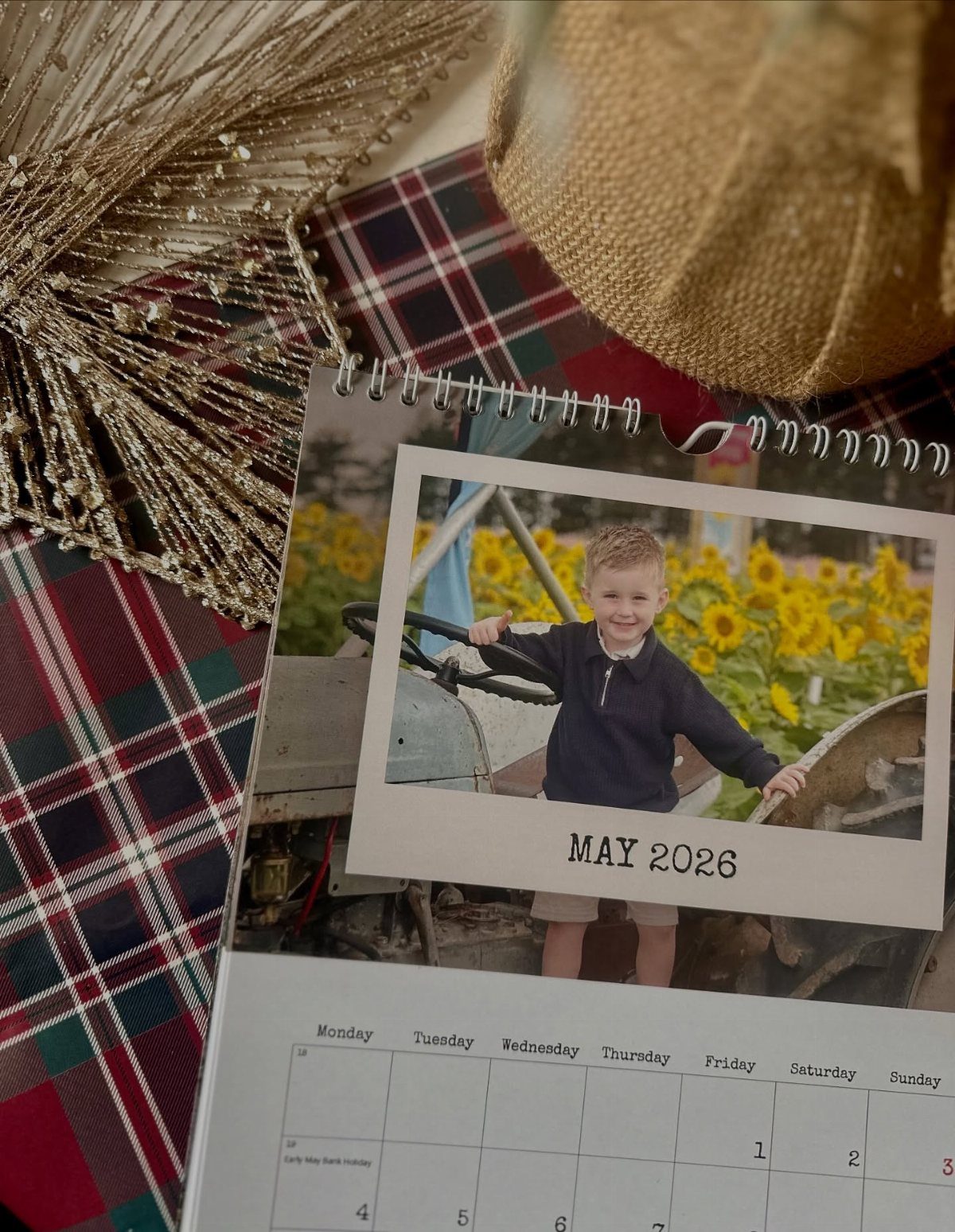 Personalized photo calendar with a boy on a tractor resting on plaid fabric.