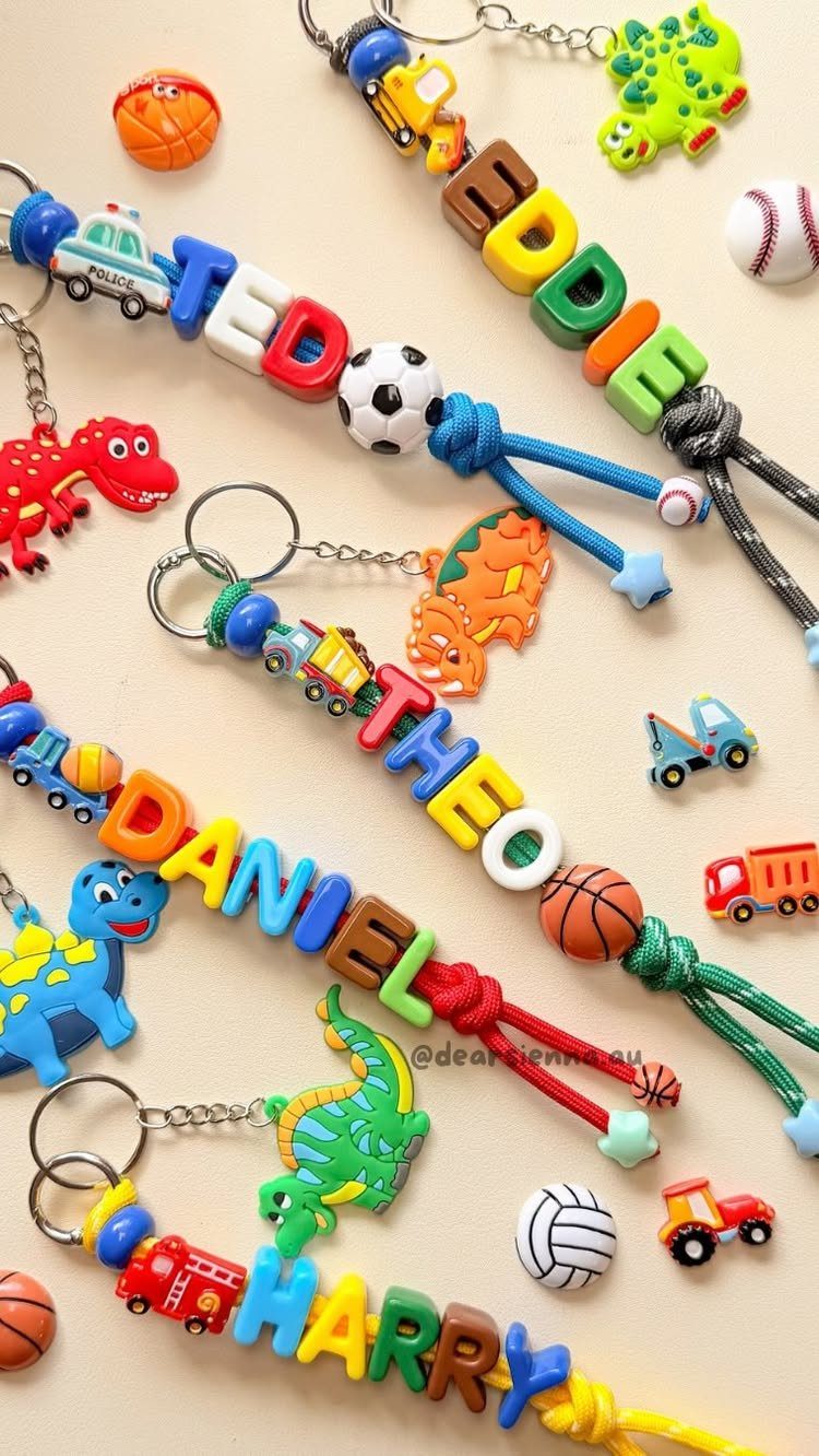 Colorful handmade beaded keychains with names and small toy charms on a light background