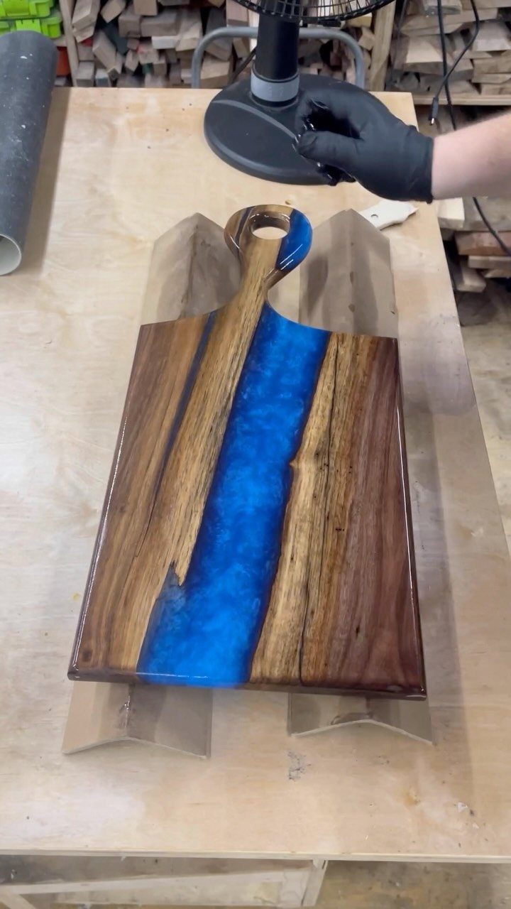 Wooden serving board with a blue resin river on a workshop table