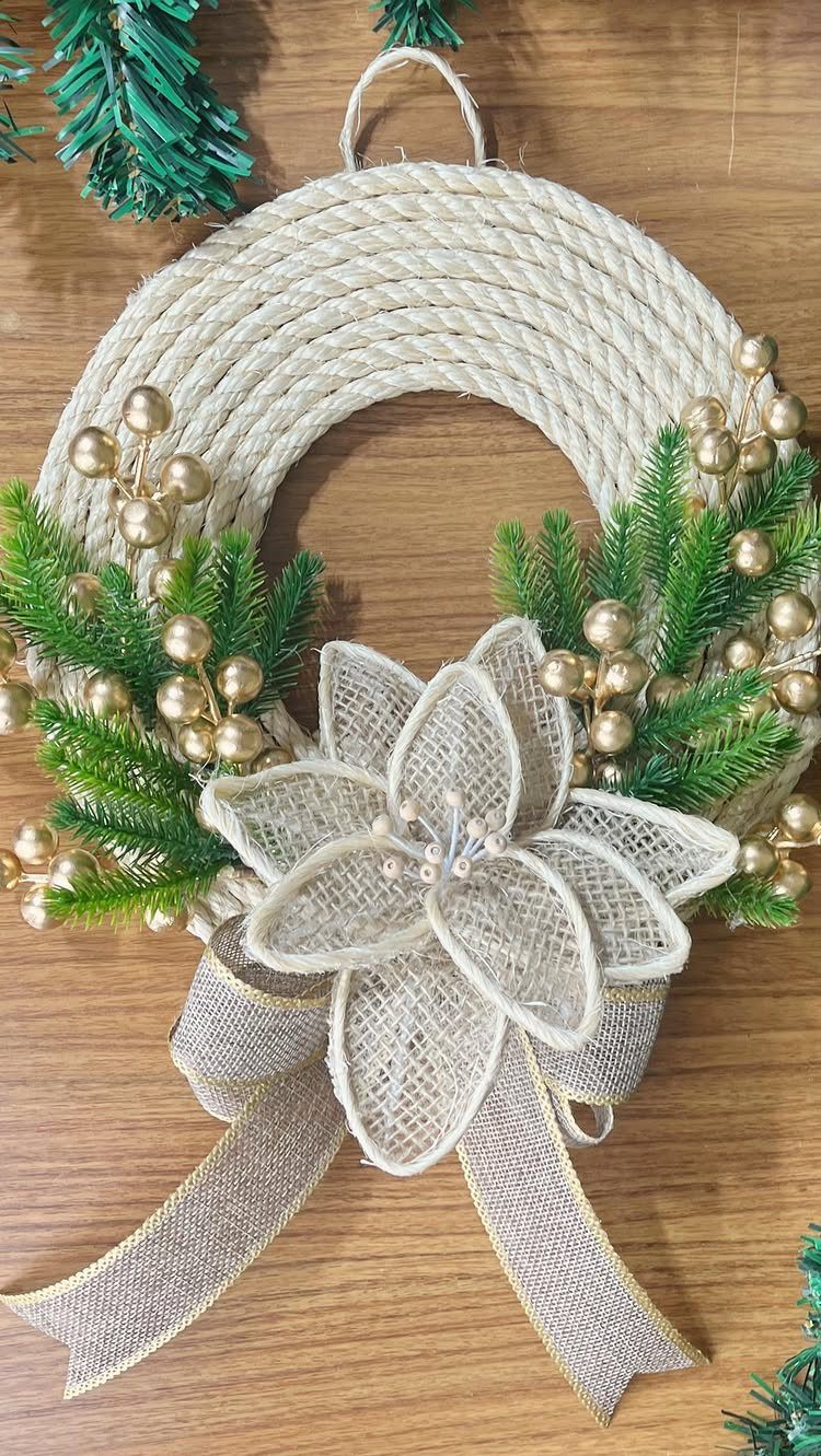 Rope wreath decorated with green pine needles, gold berries, and a burlap flower.